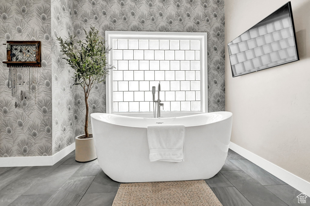 Bathroom with tile patterned floors, a wealth of natural light, and a bathtub