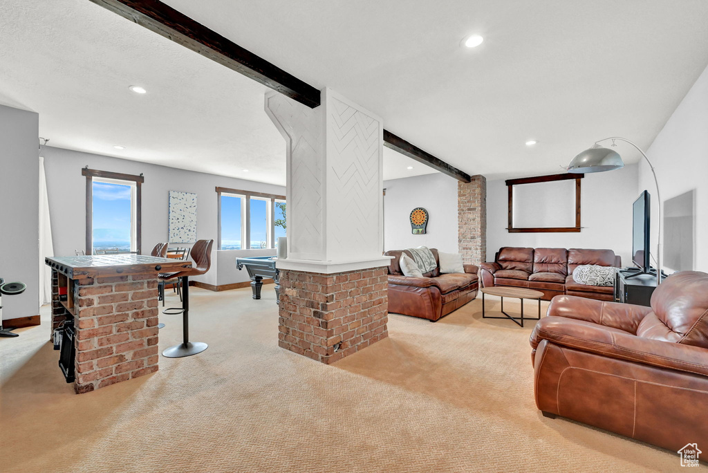 Living room featuring beamed ceiling, light carpet, brick wall, and billiards