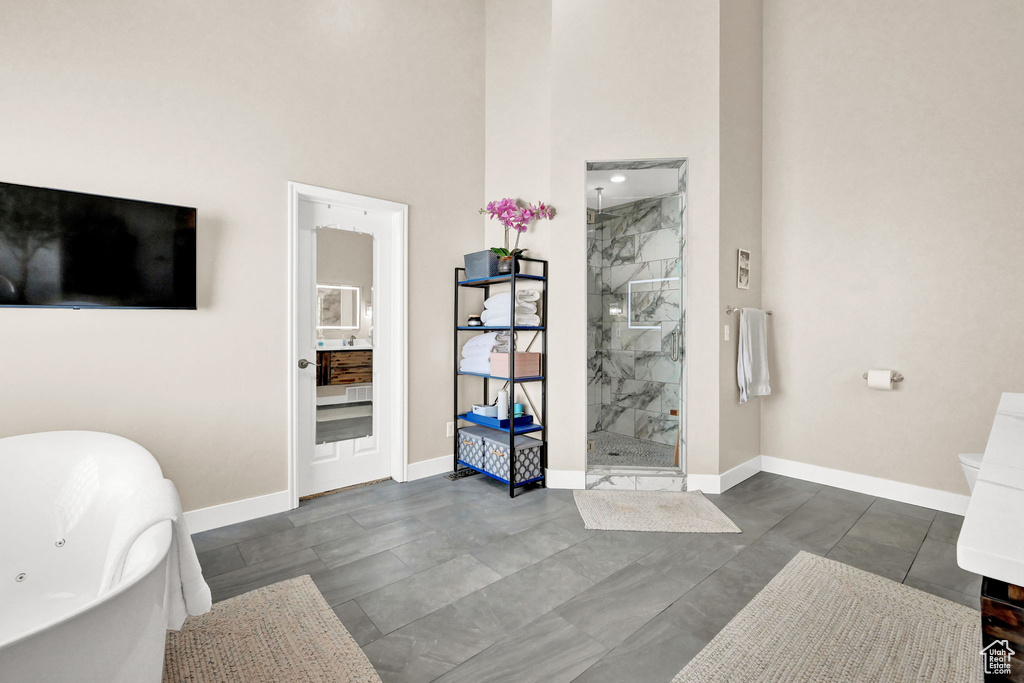 Bathroom with a shower with shower door, tile patterned flooring, toilet, vanity, and a towering ceiling