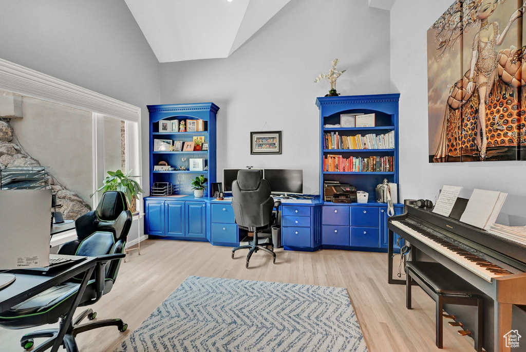 Office area featuring light hardwood / wood-style floors, built in desk, and high vaulted ceiling