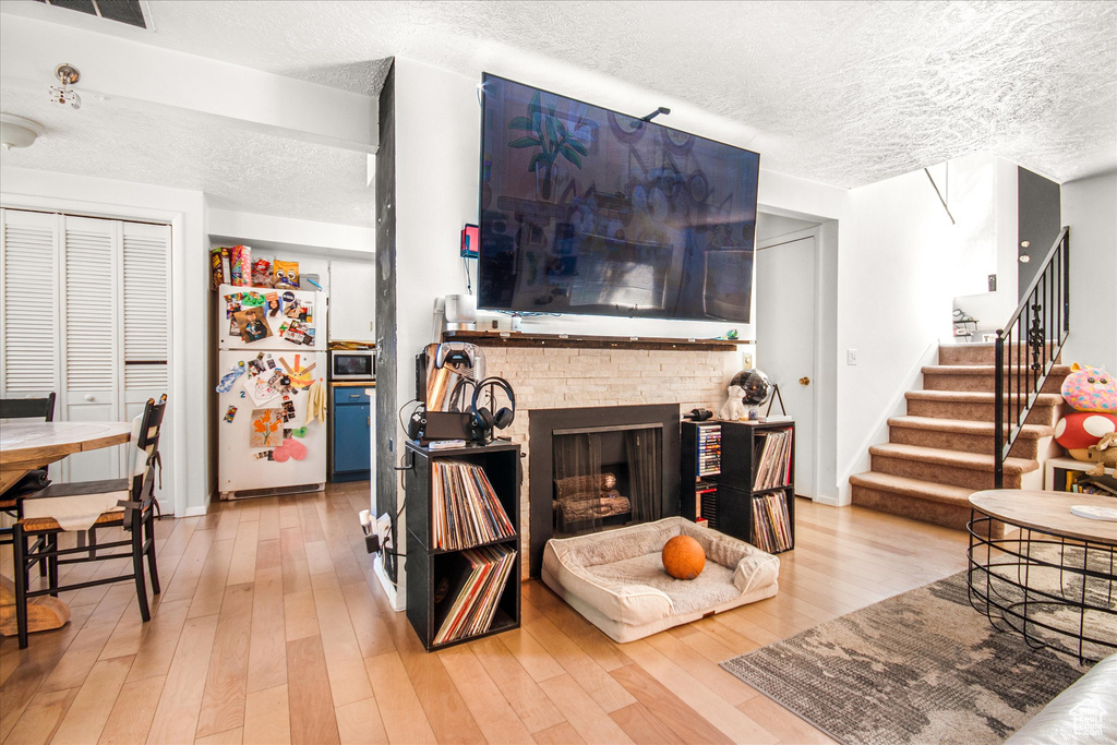 Living room featuring a fireplace, a textured ceiling, and hardwood / wood-style floors