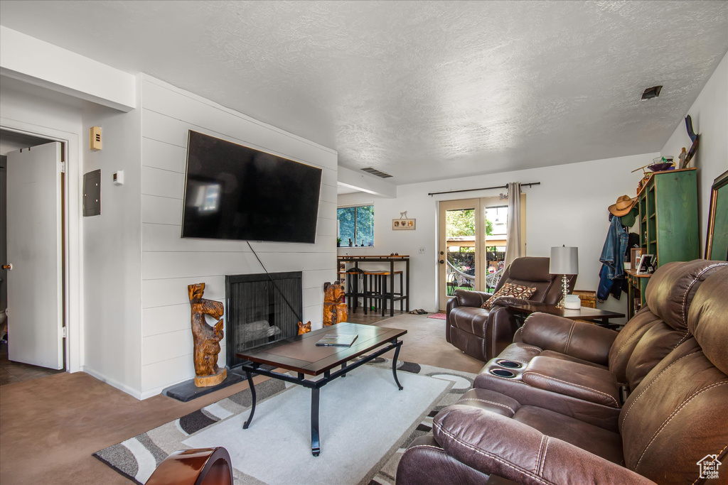 Living room with a large fireplace, carpet flooring, and a textured ceiling