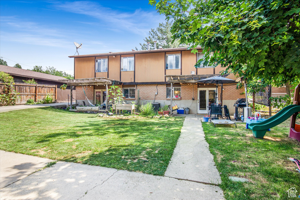 View of front of house featuring a pergola, a patio, a playground, and a front lawn