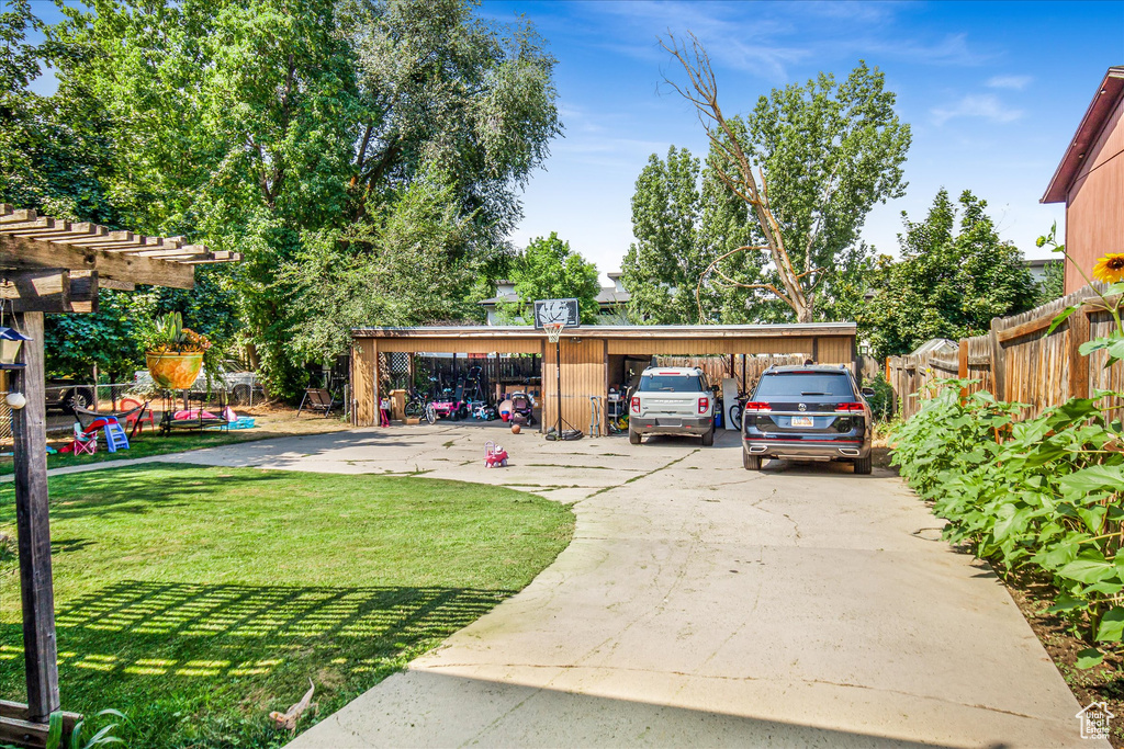 View of parking / parking lot featuring a carport and a yard