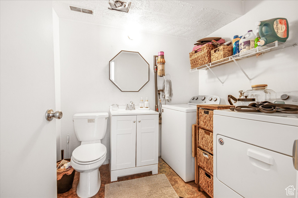 Washroom featuring sink, a textured ceiling, washer and dryer, and light tile patterned floors