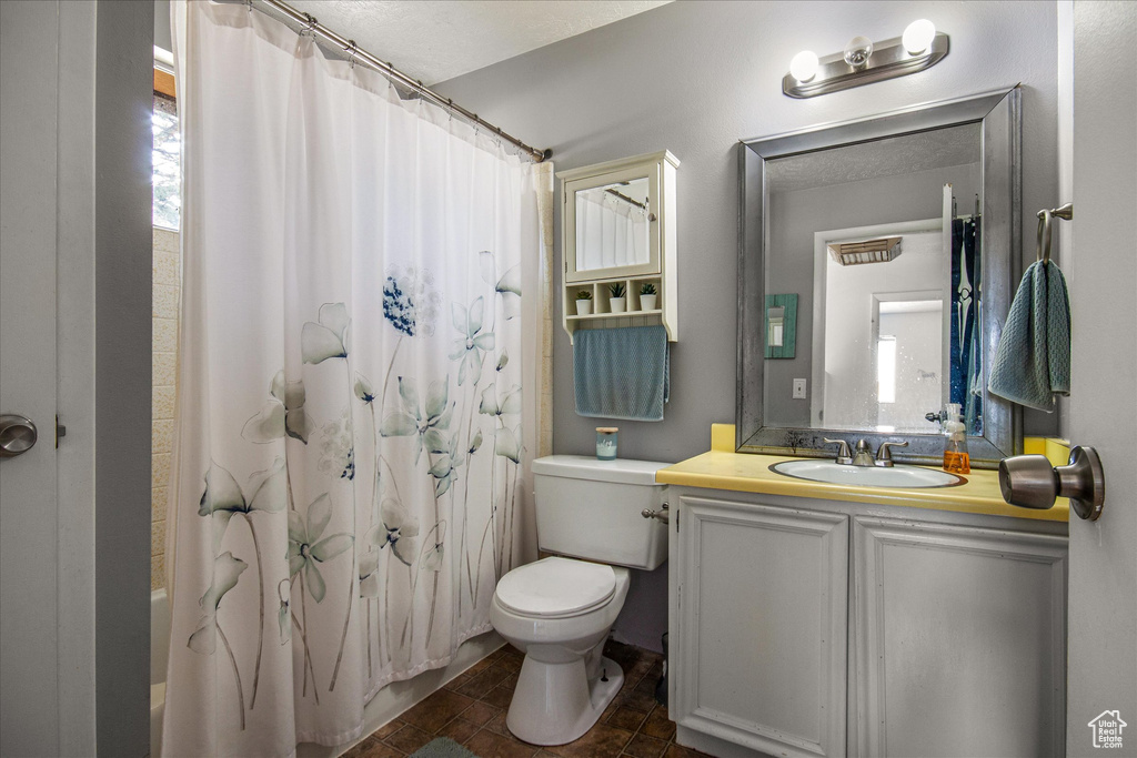 Full bathroom with tile patterned floors, toilet, vanity, and shower / tub combo with curtain