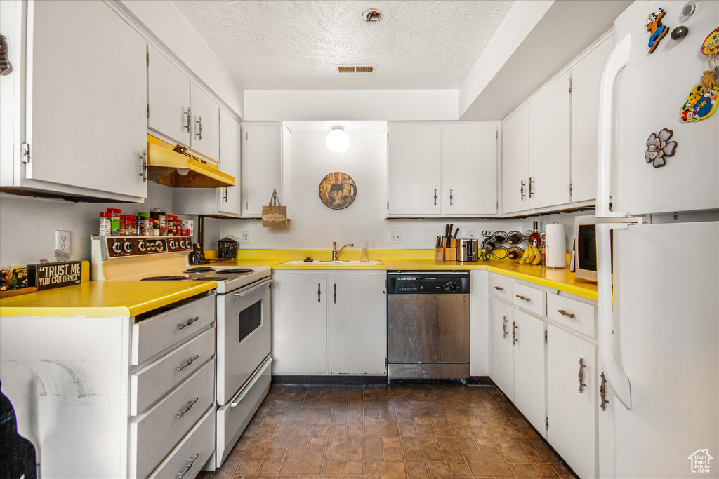 Kitchen featuring custom range hood, white cabinets, dark tile patterned flooring, and stainless steel appliances