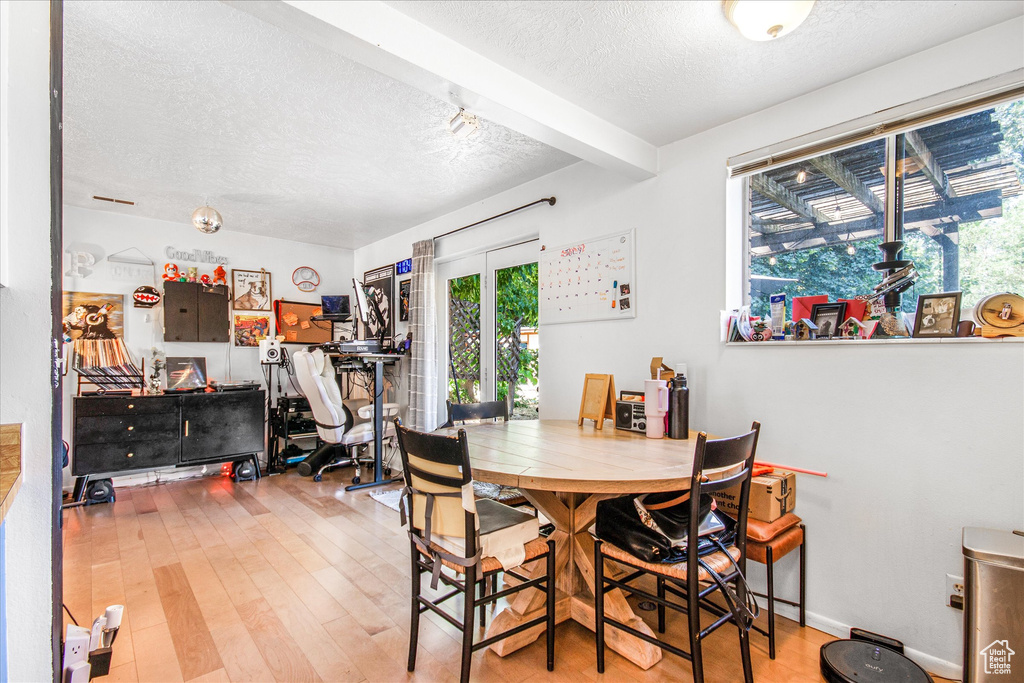 Dining area with a textured ceiling, hardwood / wood-style flooring, french doors, and beam ceiling