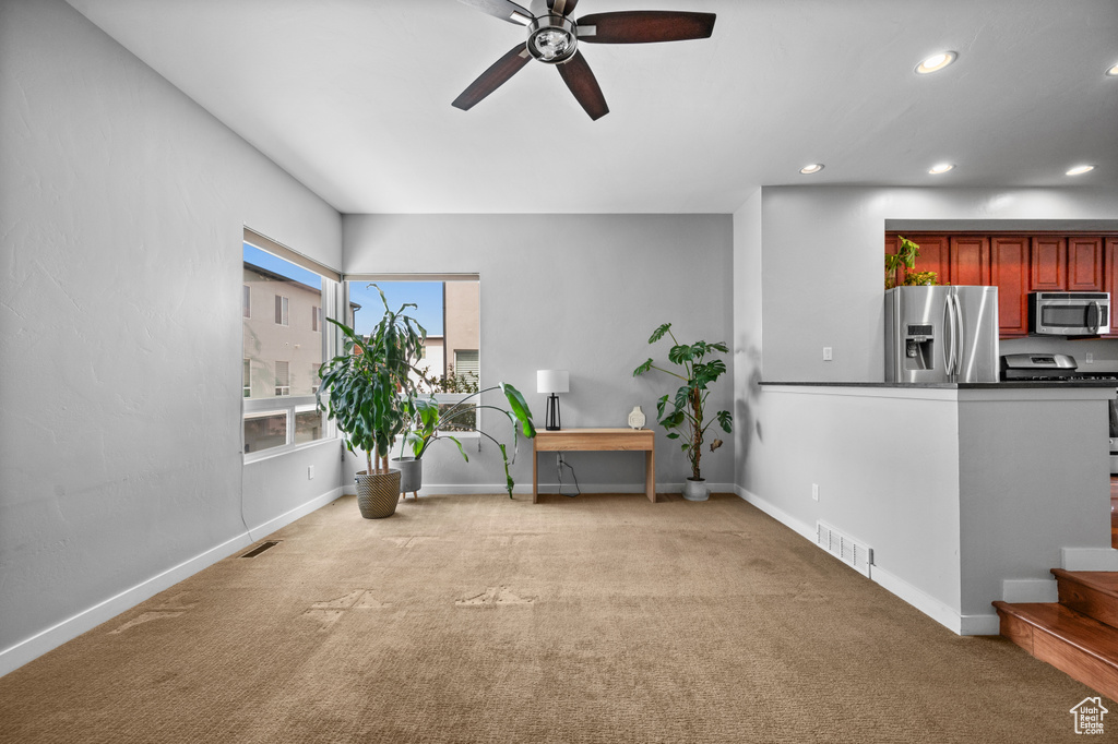 Sitting room featuring light colored carpet and ceiling fan