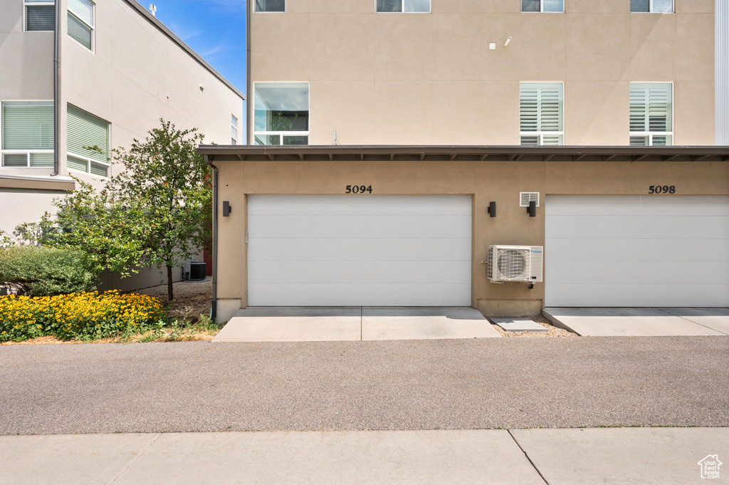 View of front of home featuring a garage and a wall unit AC