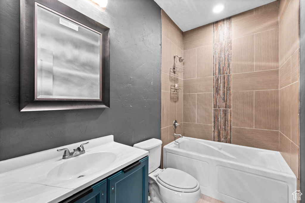 Full bathroom with tiled shower / bath combo, vanity, and toilet