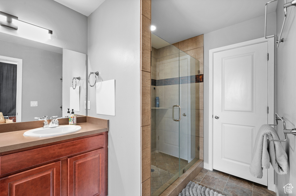 Bathroom with tile patterned flooring, a shower with door, and vanity