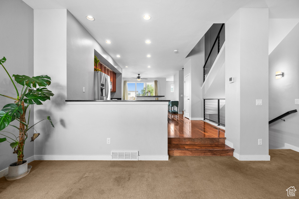 Kitchen with ceiling fan, kitchen peninsula, dark hardwood / wood-style flooring, and stainless steel fridge with ice dispenser