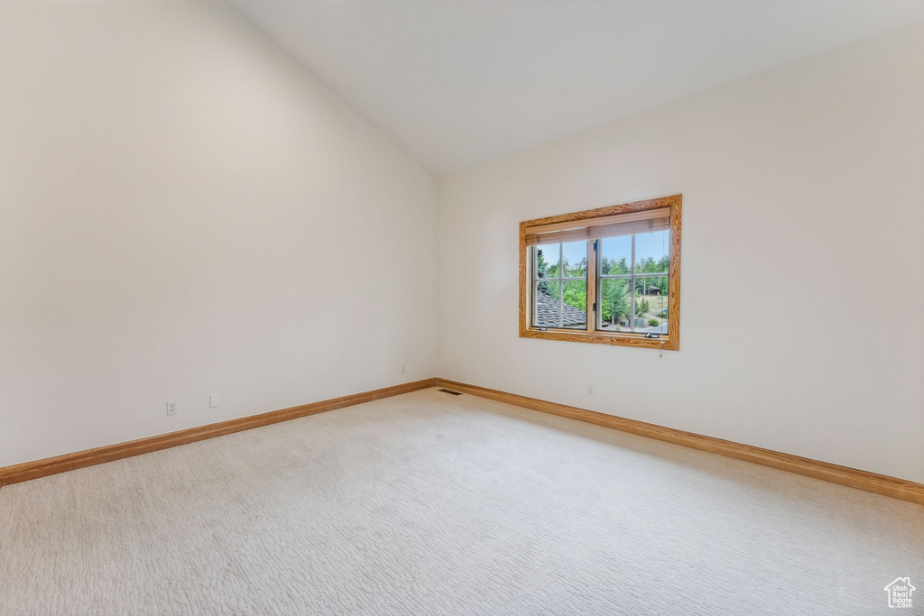 Unfurnished room featuring lofted ceiling and carpet flooring