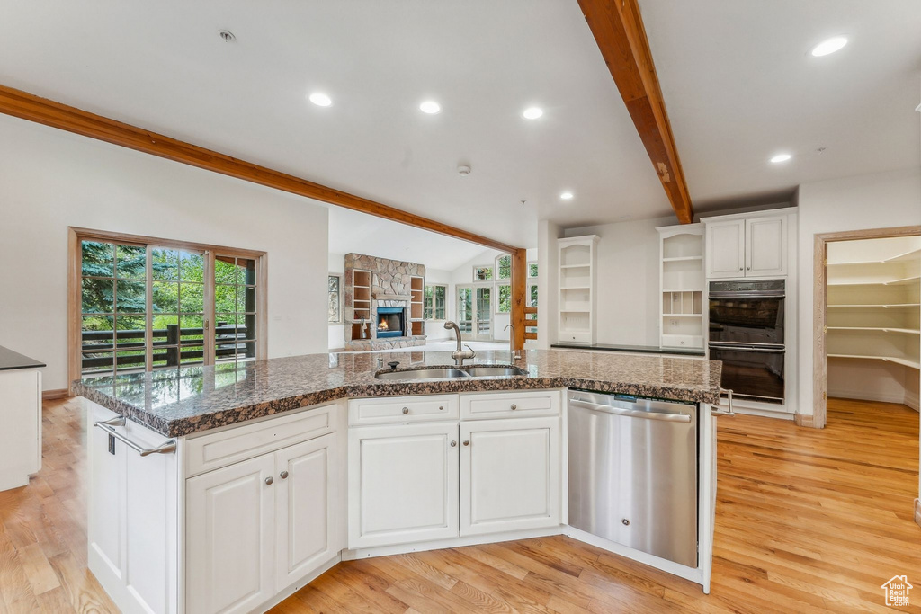 Kitchen with beam ceiling, light wood-type flooring, dishwasher, a healthy amount of sunlight, and sink