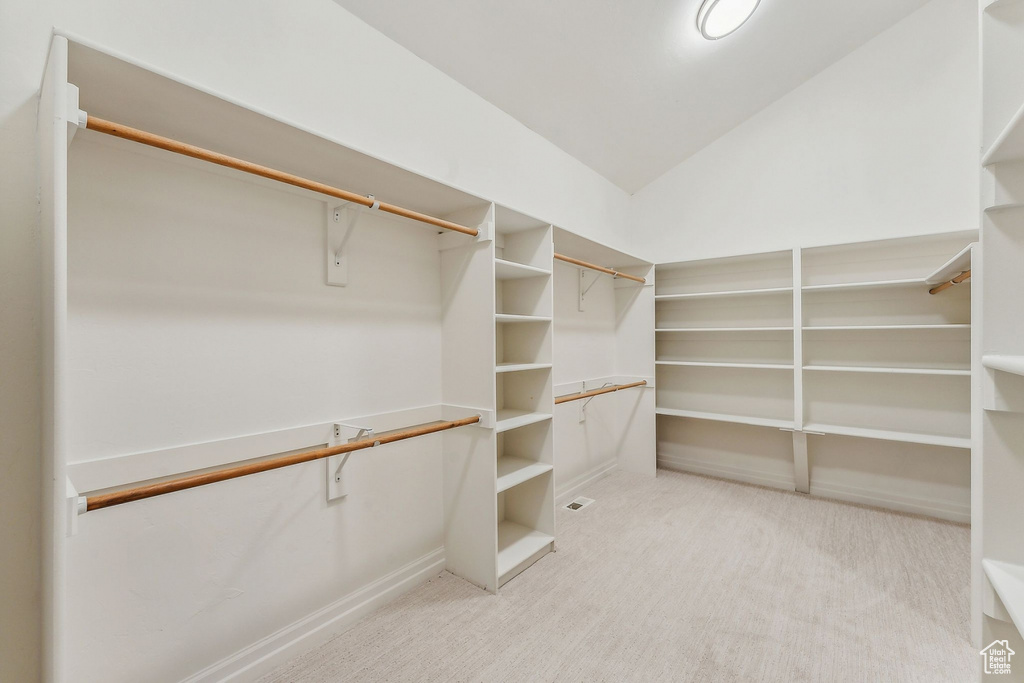 Walk in closet featuring light carpet and lofted ceiling