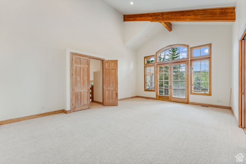 Unfurnished bedroom with beamed ceiling, light colored carpet, and high vaulted ceiling