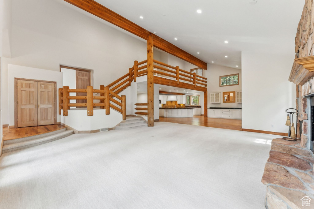 Unfurnished living room with a fireplace, wood-type flooring, and a towering ceiling