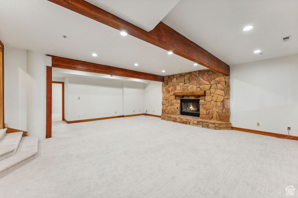 Unfurnished living room with beam ceiling, a fireplace, and light colored carpet