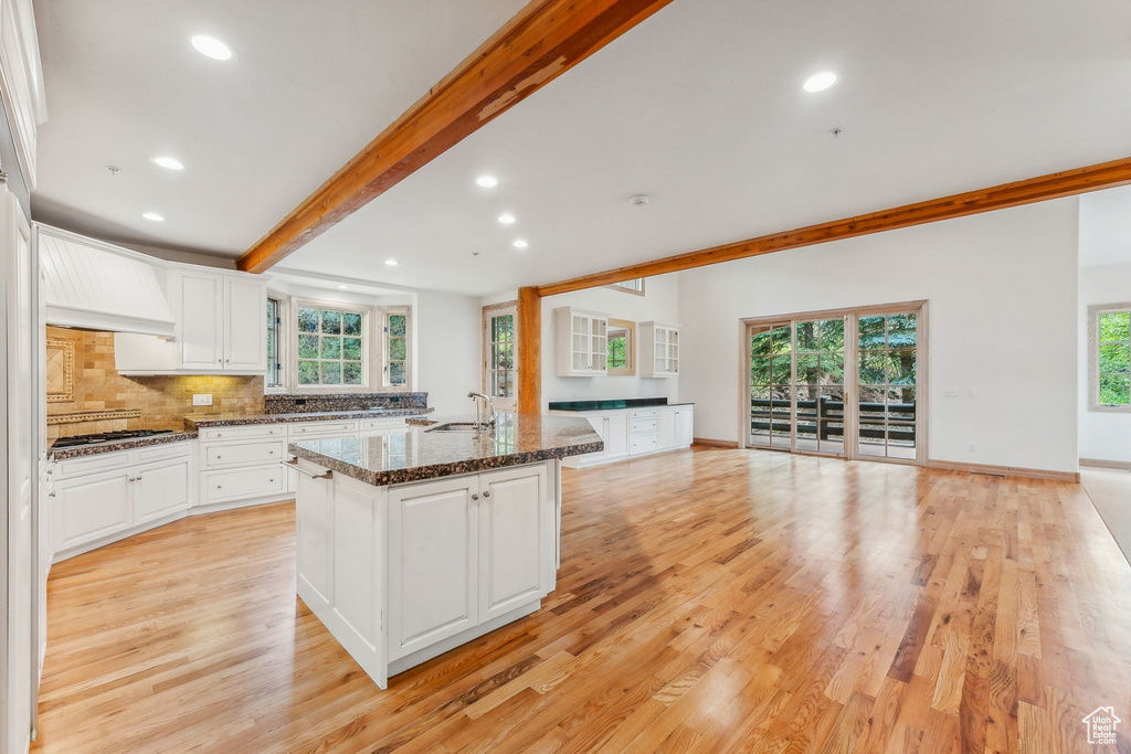 Kitchen featuring white cabinetry, premium range hood, and light hardwood / wood-style flooring