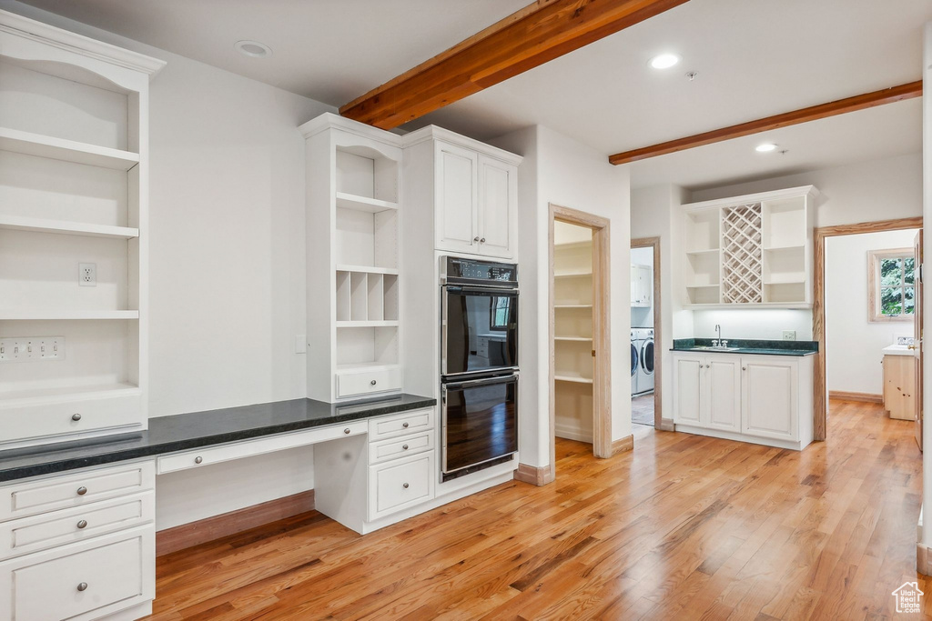 Kitchen featuring beamed ceiling, double oven, light hardwood / wood-style floors, and built in desk