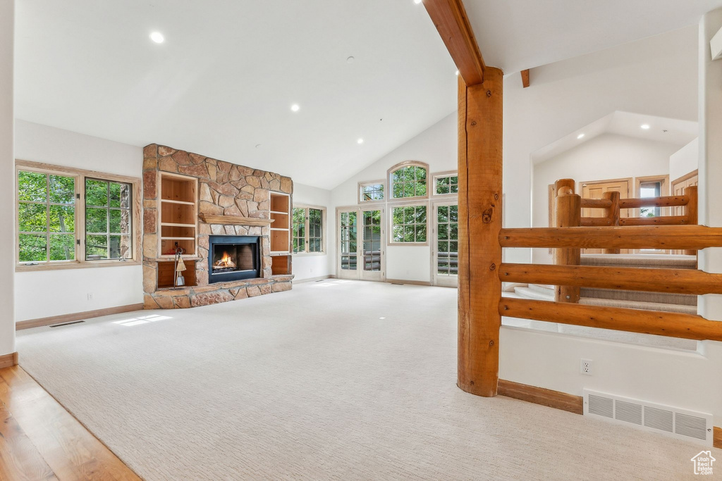 Living room featuring a stone fireplace, light carpet, and high vaulted ceiling