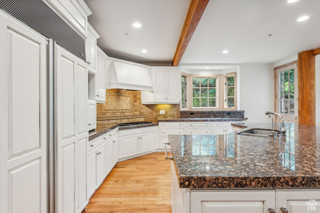 Kitchen featuring white cabinets, premium range hood, sink, and plenty of natural light