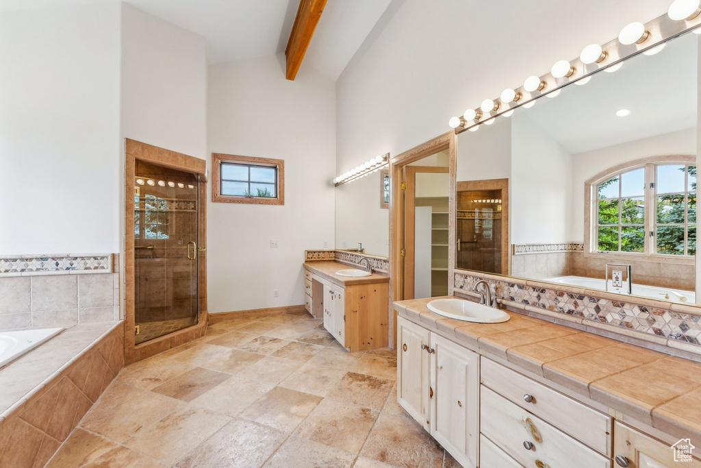 Bathroom with tile patterned flooring, shower with separate bathtub, vaulted ceiling with beams, and dual bowl vanity