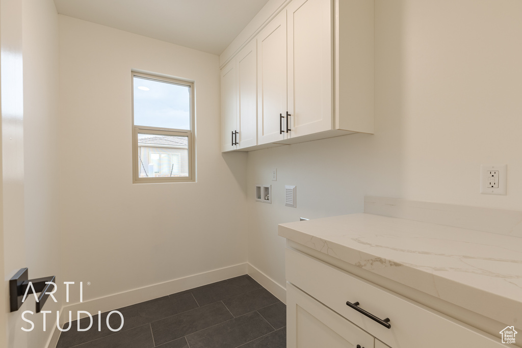 Laundry area featuring washer hookup, dark tile patterned floors, and cabinets