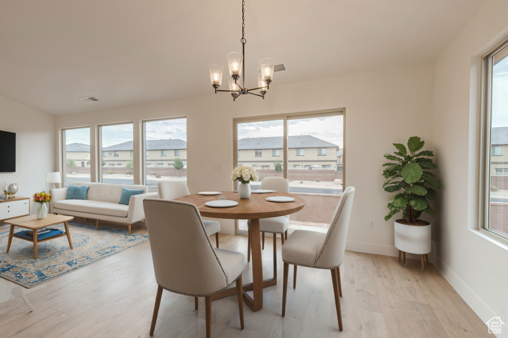 Dining room with a wealth of natural light, a chandelier, and light hardwood / wood-style floors