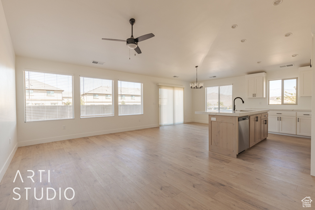 Kitchen featuring dishwasher, a center island with sink, sink, light wood-type flooring, and white cabinets