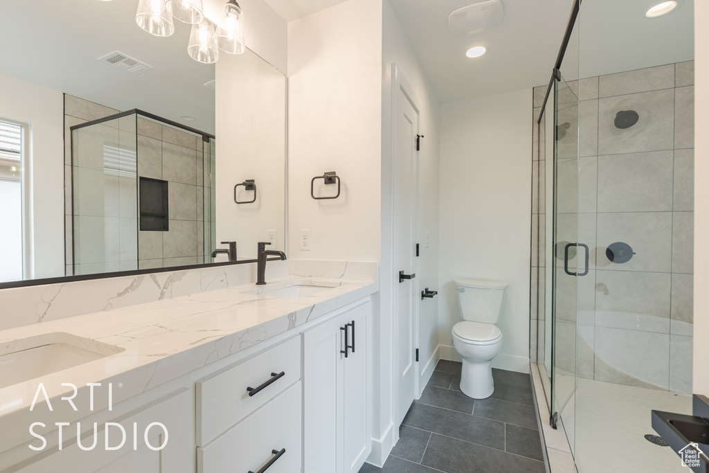 Bathroom featuring double vanity, tile patterned floors, toilet, and an enclosed shower