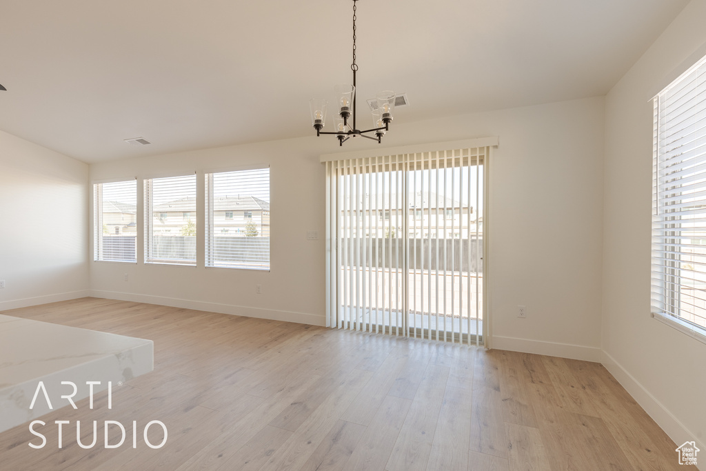 Spare room featuring light hardwood / wood-style floors and an inviting chandelier