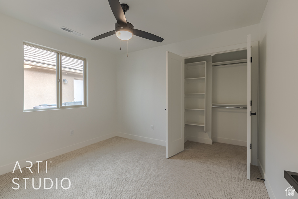 Unfurnished bedroom with light colored carpet, a closet, and ceiling fan