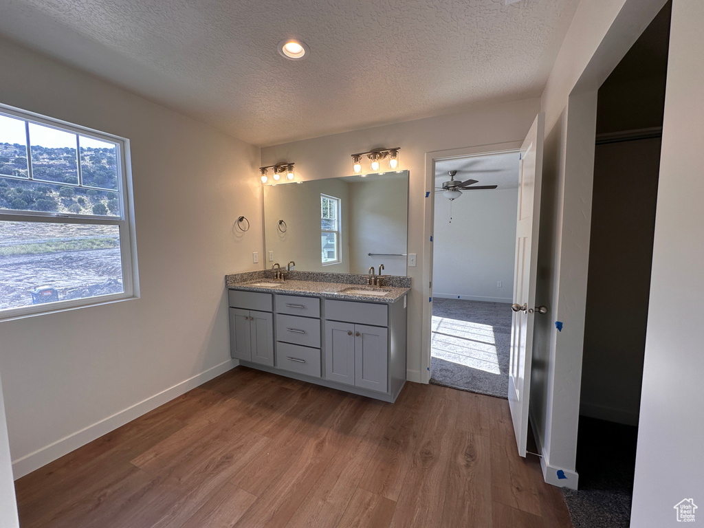 Bathroom featuring hardwood / wood-style floors, ceiling fan, a textured ceiling, and vanity