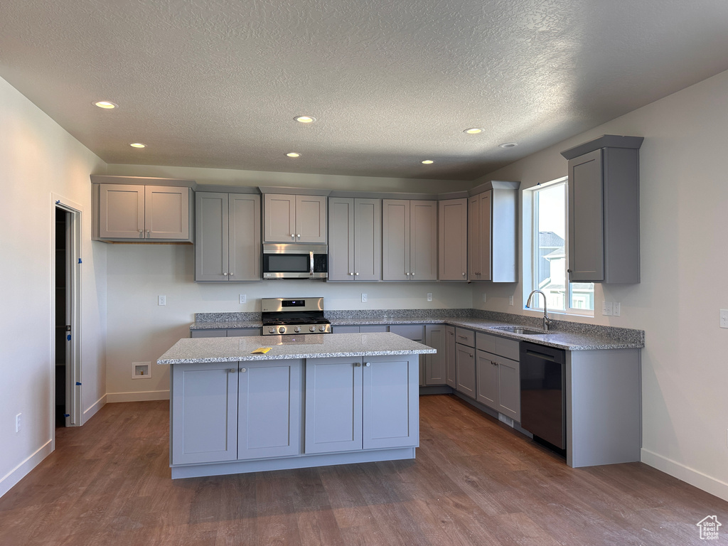 Kitchen featuring gray cabinetry, a center island, stainless steel appliances, and sink