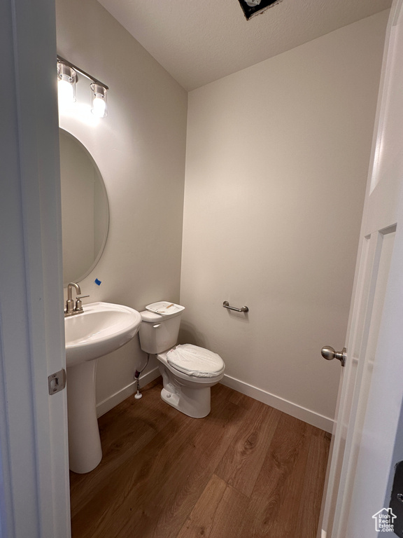 Bathroom with toilet, hardwood / wood-style flooring, and a textured ceiling