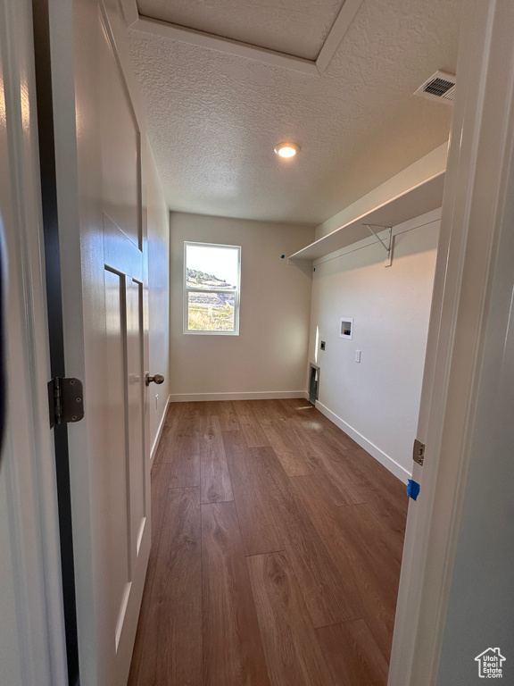 Laundry area featuring hardwood / wood-style floors, a textured ceiling, electric dryer hookup, and hookup for a washing machine