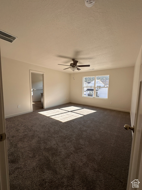 Empty room with a textured ceiling, ceiling fan, and carpet floors