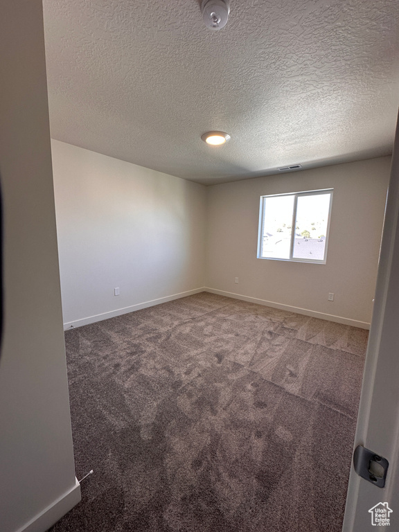 Spare room featuring a textured ceiling and carpet