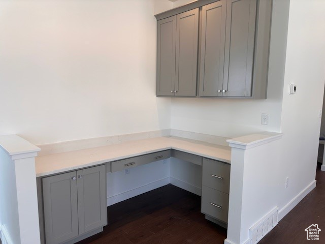 Unfurnished office featuring dark hardwood / wood-style flooring and built in desk