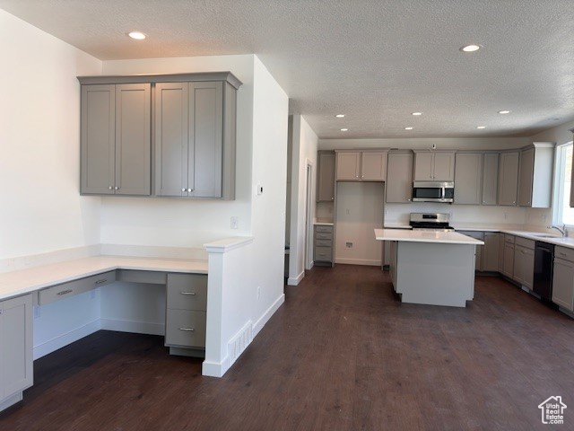 Kitchen with gray cabinets, stove, a kitchen island, a textured ceiling, and dark wood-type flooring