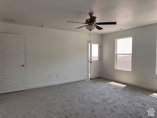 Carpeted empty room featuring a textured ceiling and ceiling fan