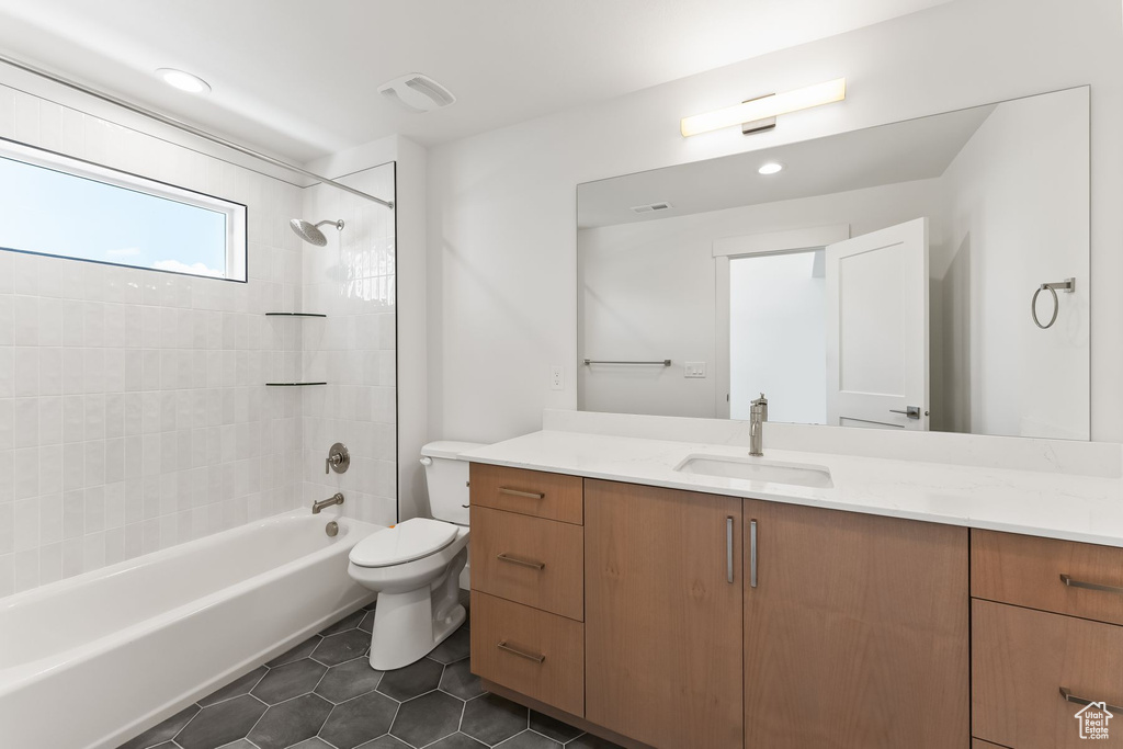 Full bathroom featuring vanity, tiled shower / bath combo, toilet, and tile patterned floors