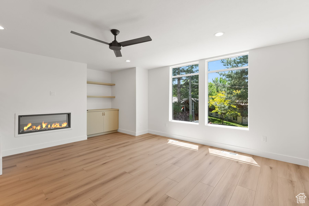 Unfurnished living room featuring light wood-type flooring and ceiling fan