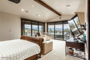 Bedroom featuring vaulted ceiling with beams and access to outside