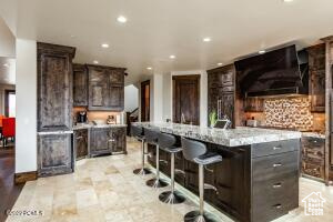 Kitchen with dark brown cabinetry, a kitchen island, a breakfast bar area, and tasteful backsplash