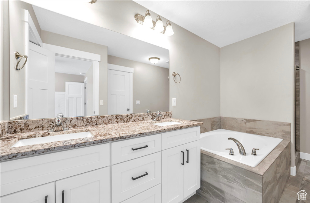 Bathroom with double vanity, tiled bath, and tile patterned floors