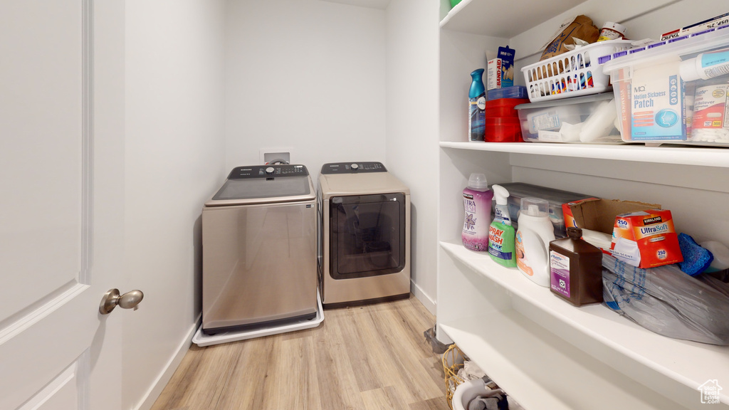 Clothes washing area featuring light hardwood / wood-style floors and washing machine and clothes dryer