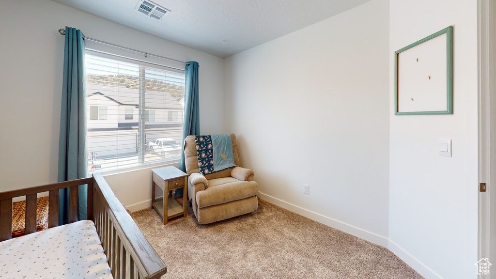 Bedroom featuring a nursery area and light colored carpet